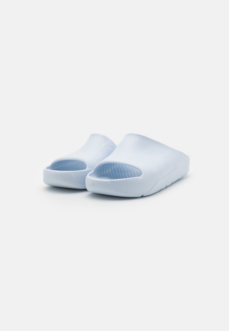 Une paire de sandales glissantes légères de couleur bleu clair avec un dessus perforé et une semelle texturée sur un fond blanc.
