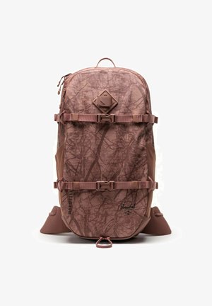 Sac à dos marron avec un motif de branches d'arbre. Ses caractéristiques incluent des bretelles ajustables, une poignée sur le dessus et un emblème en forme de diamant à l'avant.