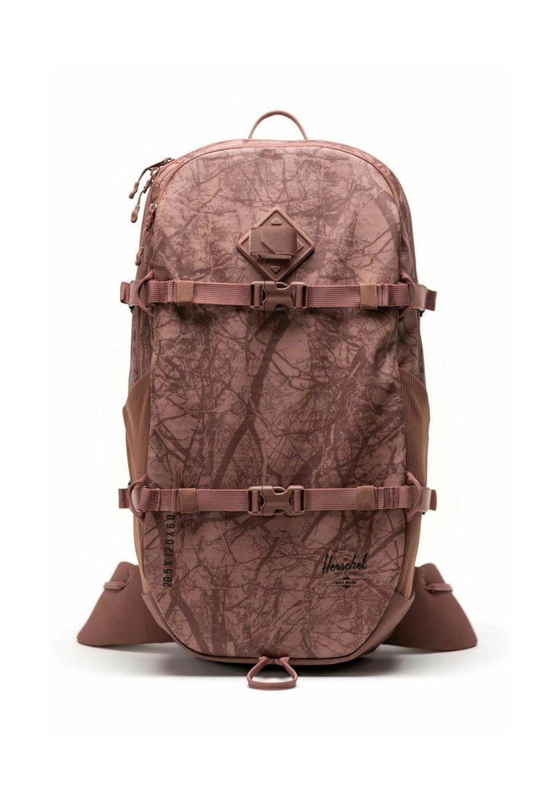 Sac à dos marron avec un motif de branches d'arbre. Ses caractéristiques incluent des bretelles ajustables, une poignée sur le dessus et un emblème en forme de diamant à l'avant.