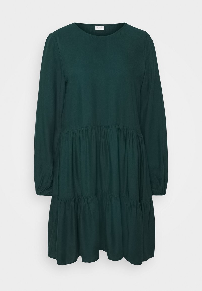 Tumma vihreä, pitkähihainen mekko, jossa on pyöreä pääntie. Mekossa on kerroksellinen hame ja rypytettyjä yksityiskohtia tekstuurin luomiseksi. Pehmeä ja sileä kangas.