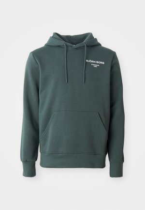 Tumši zaļš hoody ar priekšējo kabatu, šņorēm un baltu uzrakstu "BJÖRN BORG Stokholm 1956" kreisajā krūtī.