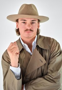 Brown trench coat with a double-breasted design, worn over a blue and white striped shirt. Gray felt wide-brim hat. Light skin, mustache.