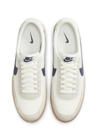 Ténis de pele branca com swoosh azul-marinho, acentos texturizados e atacadores em creme. Apresenta uma sola de borracha em cor de gengibre e forro interior respirável.