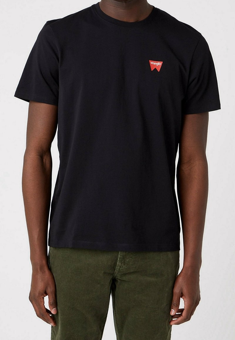 Černé bavlněné tričko s kulatým výstřihem. Na levé části hrudníku má červené obdélníkové logo. Krátké rukávy a standardní střih.