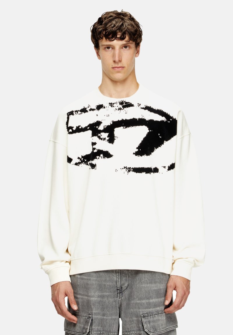 Sudadera blanca con un amplio diseño abstracto negro en la parte frontal. Tiene mangas largas, cuello redondo y un corte relajado.