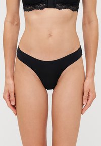 Svart bikini-bunn med et stilrent design, tynne sidestrikker og glatt tekstur. Har minimal dekning og ingen synlige detaljer.