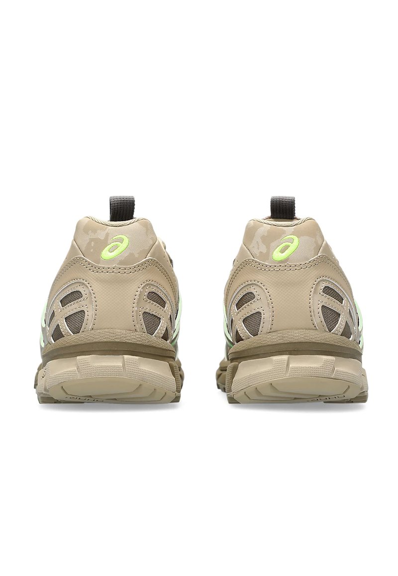 Zapatillas deportivas en tono marrón con paneles de malla, suela texturizada y un logo reflectante. El diseño incluye una mediasuela acolchada y una lengüeta para tirar.