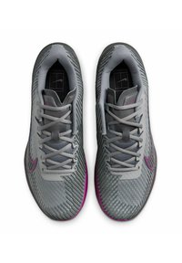 Zapatillas deportivas grises con un empeine texturizado, acentos morados en contraste, cordones planos y un diseño de perfil bajo adecuado para el rendimiento.