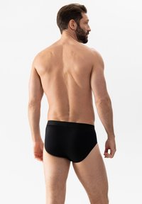 Schwarze Slips mit enger Passform und glatter Textur. Der Bund ist elastisch und bietet Komfort sowie Halt ohne sichtbare Nähte.