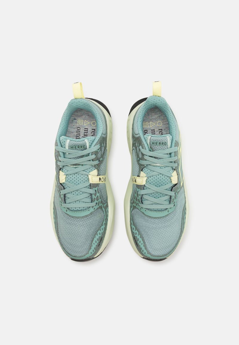 Zapatillas deportivas de color azul claro con parte superior de malla, acentos texturizados y tiradores amarillos. Cuentan con una suela acolchada y cordones para un ajuste seguro.