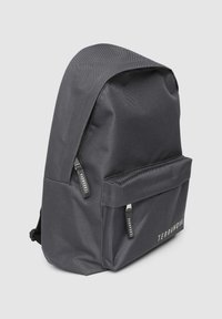 Czarny plecak z nylonu o gładkiej fakturze, zaokrąglonym kształcie, przedniej kieszeni na zamek oraz z logo na zapięciach. Charakteryzuje się prostym, nowoczesnym designem.