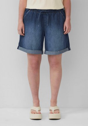 Spijkershorts met een elastische tailleband en trekkoord, met omgeslagen zoom, in een donkerblauwe wassинг, gecombineerd met lichtgekleurde platform sandalen.