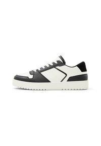 White and black sneaker featuring a smooth leather finish, textured accents, round toe, and a cushioned sole with patterned tread.