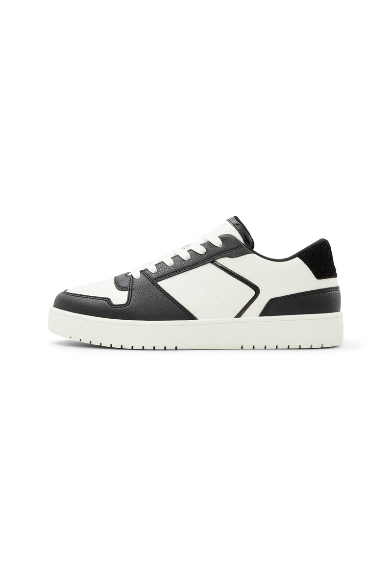 White and black sneaker featuring a smooth leather finish, textured accents, round toe, and a cushioned sole with patterned tread.