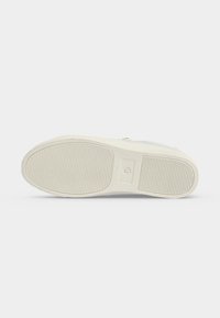 Semelle d'une basket blanc cassé avec texture côtelée au niveau du talon et des orteils, affichant la taille 37 sur une surface plane et propre.
