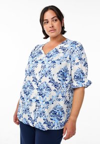 Weißes Button-Up-Bluse mit blauen Blumenmustern. Verfügt über einen V-Ausschnitt und kurze, rüschendetails Ärmel. Aus leichtem Stoff gefertigt.