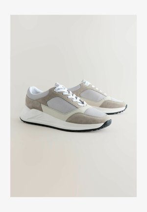 Grey and white sneakers feature mesh and suede materials, a rounded toe, flat laces, and a textured rubber sole with a slight heel.