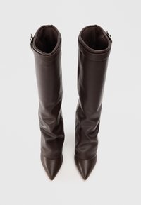 Bottes en cuir marron jusqu'au genou avec un design ample, des pointes effilées, une texture lisse et une accentuation par boucle en haut.