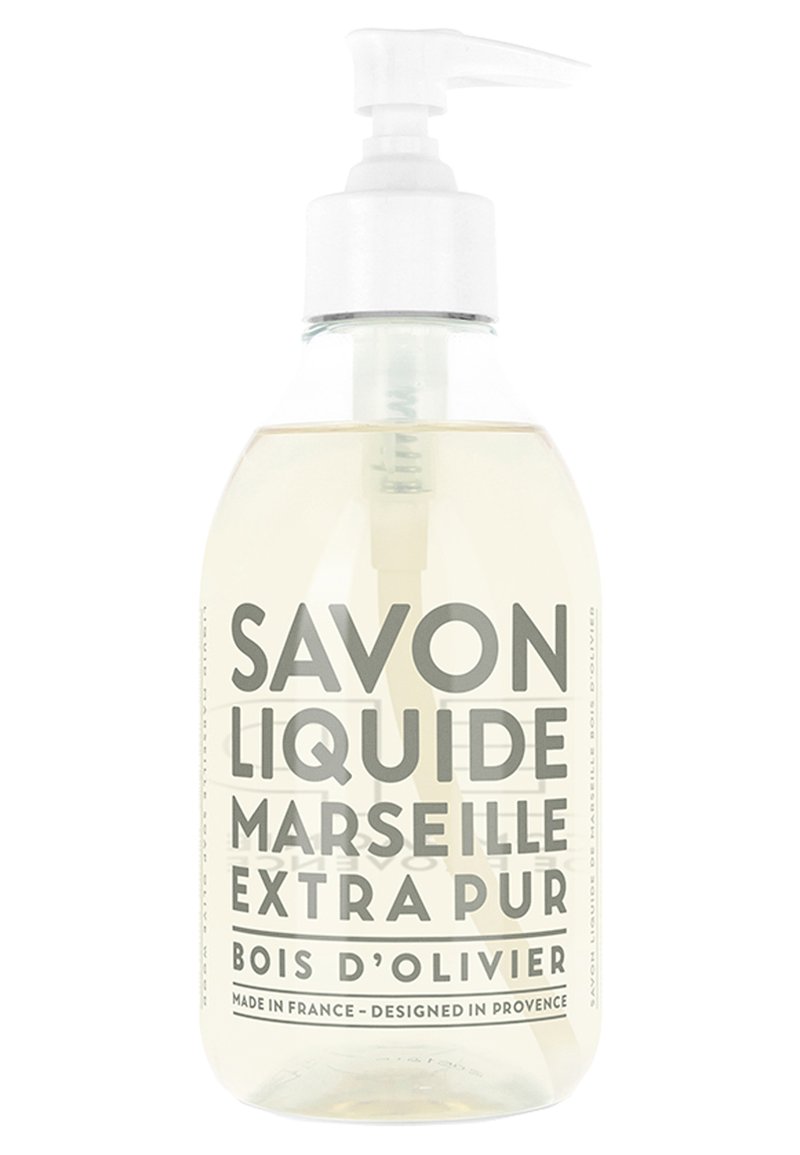 Clear glass bottle with a white pump dispenser, filled with liquid soap. Label features gray text: "Savon Liquide Marseille Extra Pur Bois d'Olivier."