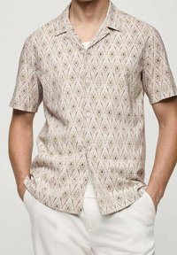 Koszula na krótki rękaw zapięta na guziki w jasnobeżowym kolorze, z falistym wzorem w różnych pastelowych odcieniach. Gładka faktura tkaniny, luźny krój.