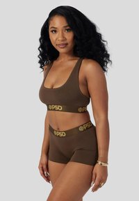 Brunt undertøysett med en BH med rund hals og bokserinspirerte shorts. Har mykt stoff og brede elastiske bånd med logoaksenter i gull.
