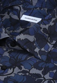 Chemise à manches courtes bleu marine avec motifs floraux. Elle présente un col classique, des boutons noirs et une étiquette portant l'inscription "seidensticker".
