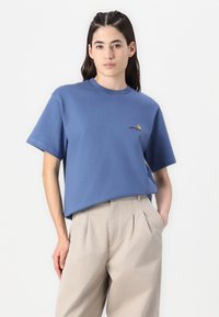 Blaues Baumwoll-T-Shirt mit Rundhalsausschnitt und kurzen Ärmeln, mit einem gestickten Logo in Rot und Gelb auf der linken Brust.
