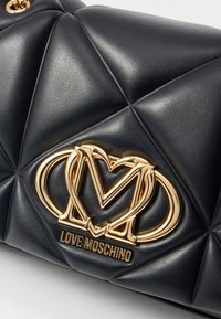 Navy quilted faux leather handbag with gold-tone "Love Moschino" logo and heart motif; features diamond pattern and smooth texture.