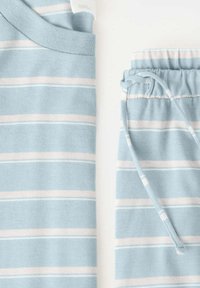Haut en maille bleu clair et pantalon à cordon assorti avec des rayures horizontales blanches et roses sur fond blanc.