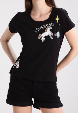 Black t-shirt featuring colorful embroidered patches, including a unicorn, a banner with text, and star designs. Short sleeves and classic fit.