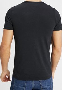 Svart t-shirt med kort ärm, bomullsmaterial, figursydd design, rundad halsringning, slät textur, inga synliga mönster eller logotyper, vy från baksidan.