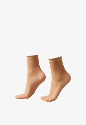 Calcetines tobilleros desnudos con patrón de lunares, con borde ondulado, fabricados en material ligero y diseñados para ajustarse cómodamente alrededor del tobillo.