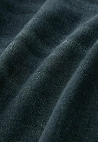 Tume sinine denimpind, millel on pehme tekstuur, kus on peenikesed toonilised varieeruvad ja sile, veidi läikiv pind.