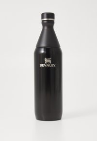 Bouteille d'eau en acier inoxydable noir avec une forme conique, un large fond et un couvercle à vis. Présente un logo argenté "STANLEY" à l'avant.