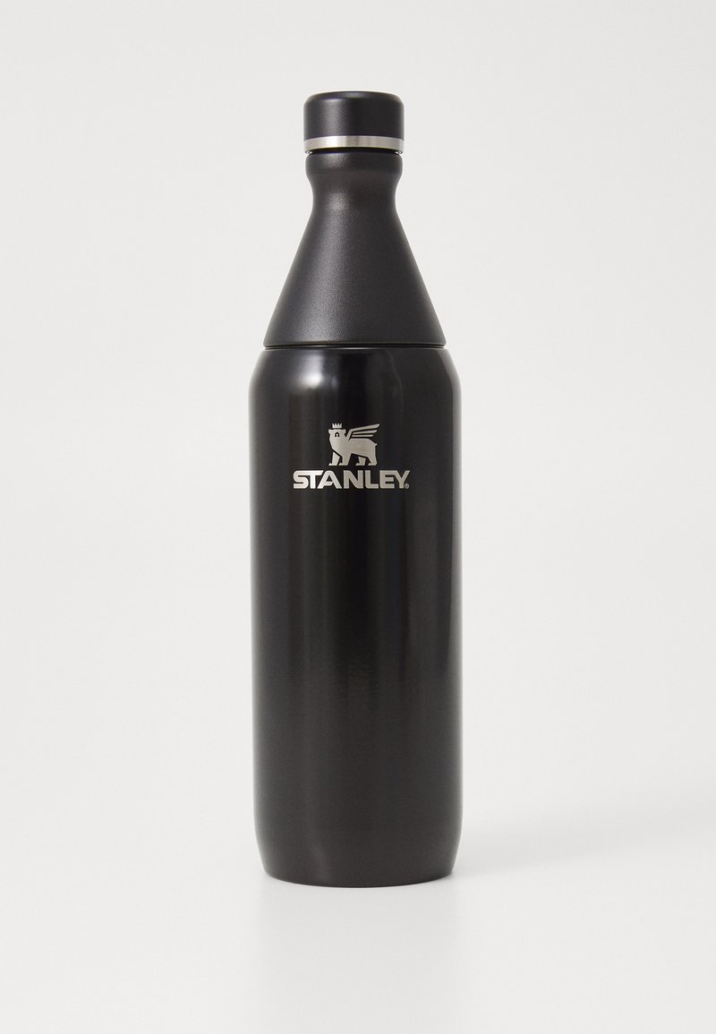 Μαύρο ανοξείδωτο μπουκάλι νερού με κωνικό σχήμα, φαρδιά βάση και καπάκι που βιδώνει. Διαθέτει ασημένιο λογότυπο "STANLEY" μπροστά.
