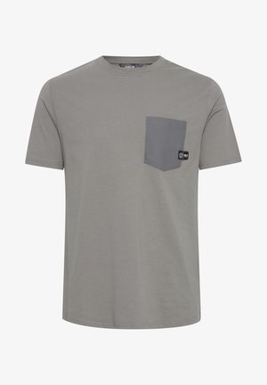 Šedé tričko s krátkym rukávom vyrobené z bavlny. Má kontrastnú šedú náprsné vrecko na ľavej strane hrudníka a malú značkovú etiketu na vrecku.