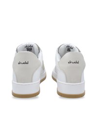 White athletic shoes with a beige heel accent, smooth leather upper, textured collar, and rubber sole featuring a patterned grip.