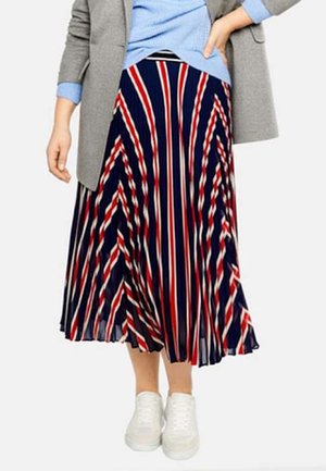Spódnica midi plisowana z pionowymi paskami w kolorach granatowym, czerwonym i białym, wykonana z lekkiego materiału. W zestawieniu z białymi trampkami i szarą marynarką.