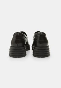 Black leather shoes with a rounded design, featuring a thick, ridged sole and minimal detailing. Smooth texture with a polished finish.