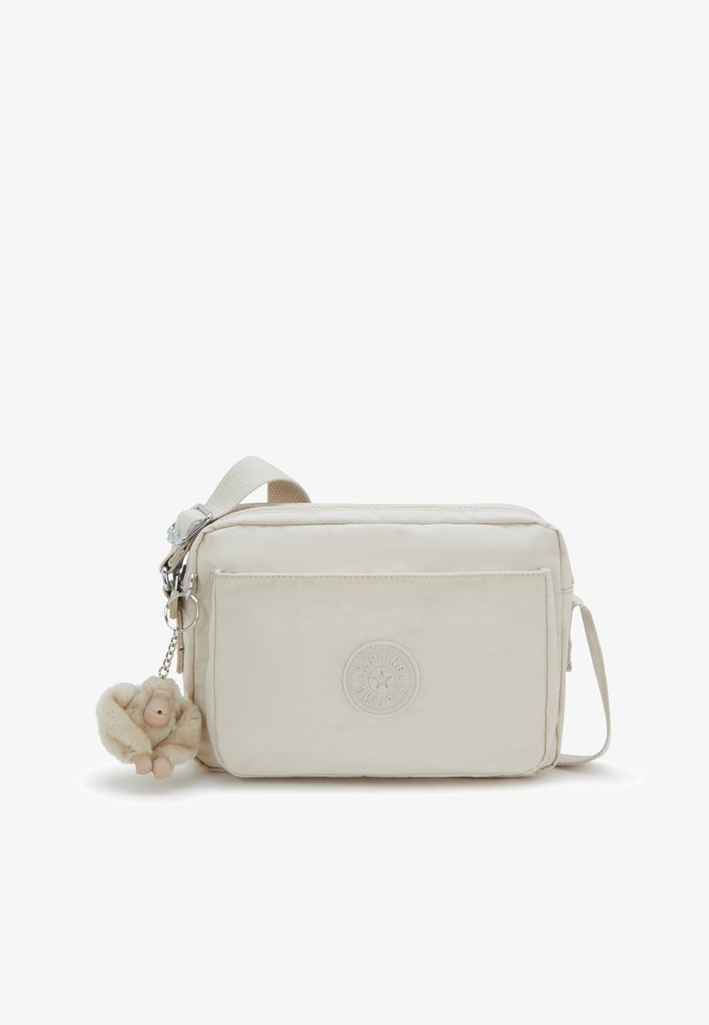 Borsa a tracolla beige realizzata in tessuto leggero, con superficie testurizzata, tasca frontale, patch con logo e decorazione di un portachiavi a forma di scimmia pelosa.