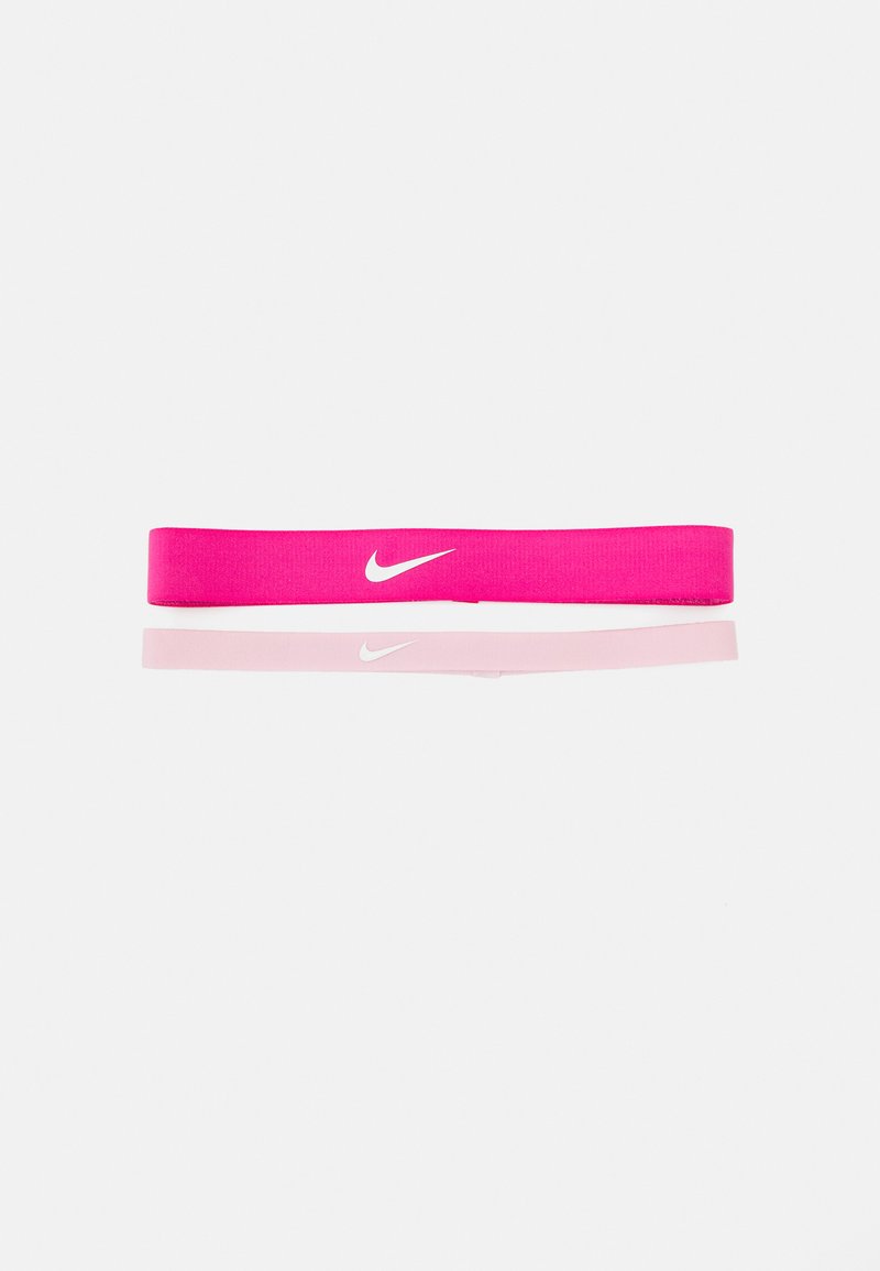 Nike športna trakica za glavo v svetlo roza barvi z belim Swoosh logotipom. Narejena iz elastičnega materiala, ima gladko teksturo in preprost dizajn.
