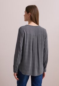 Gestreepte blouse met lange mouwen in marineblauw en wit, met een relaxte pasvorm en achterkant met plooidetail, voorzien van een ronde halslijn en knoopmanchetten.