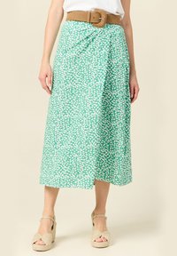 Groene midi rok met een wit abstract patroon, vastgemaakt met een bruine suède riem. Zachte stof met een flowy ontwerp en een zijschuif.