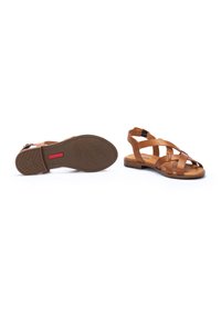 Sandales en cuir marron avec des lanières croisées, bout ouvert et boucle à la cheville. Semelle plate avec un motif de feuille au fond.