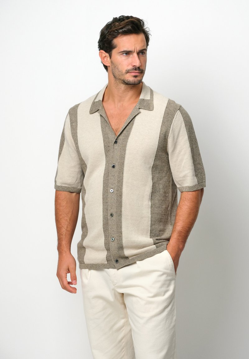 Camicetta a maniche corte con bottoni in beige e marrone chiaro, caratterizzata da righe geometriche, colletto e una vestibilità comoda.