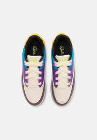Baskets à lacets avec une base en cuir crème, des accents multicolores en bleu, violet et jaune, avec une semelle en caoutchouc texturée et des détails de logo.