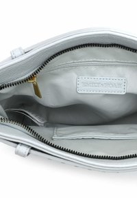 Hellgraues Lederhandtaschen-Innere mit einer Reißverschlusstasche, einem glatten Stofffutter und einem Markenetikett, ausgestattet mit schwarzem Reißverschluss und Naht.