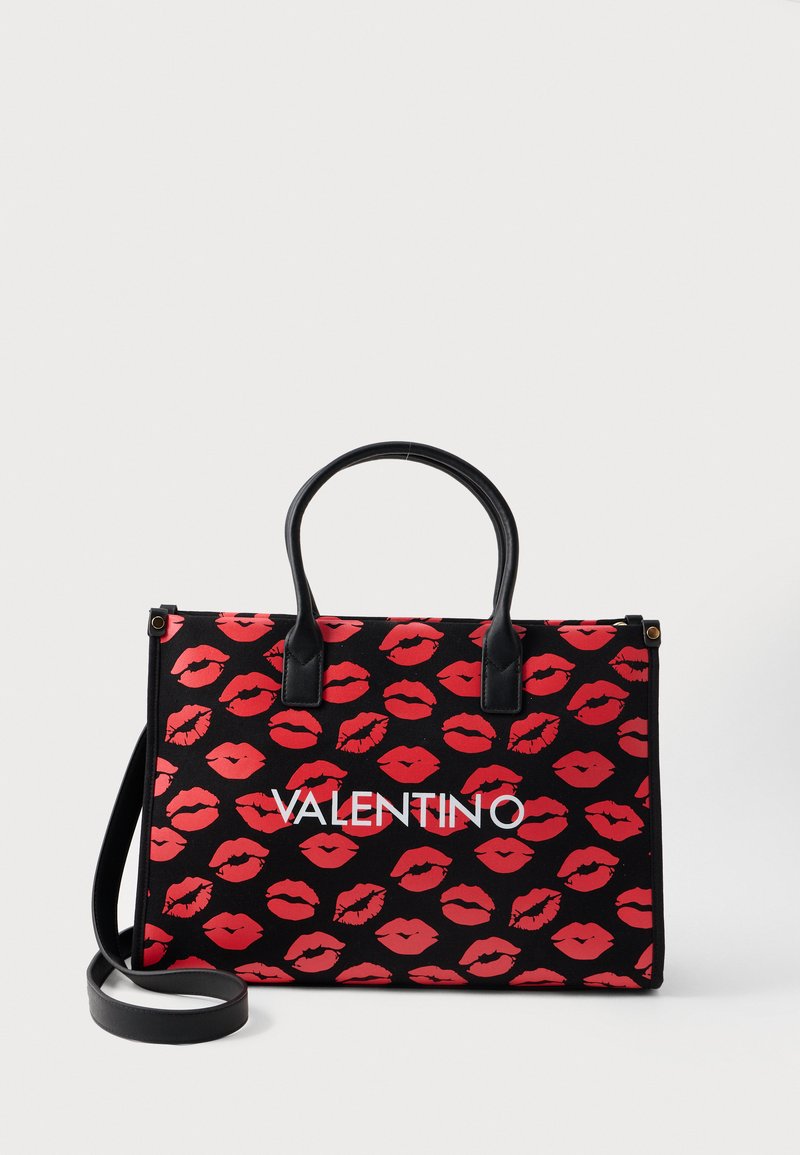 Black tote bag with red lip print, featuring two black handles and a removable shoulder strap. Prominent white "VALENTINO" logo on front.