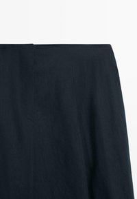 Jupe bleu marine foncé avec une taille haute et des détails de coutures épurés et minimalistes sur un fond blanc.