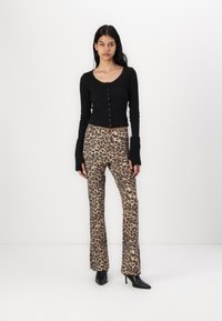 Svart avkortet cardigan med knappefront, med ribbede langermede ermer. Leopardmønstret bredbukse i beige og brune toner med en glatt tekstur.